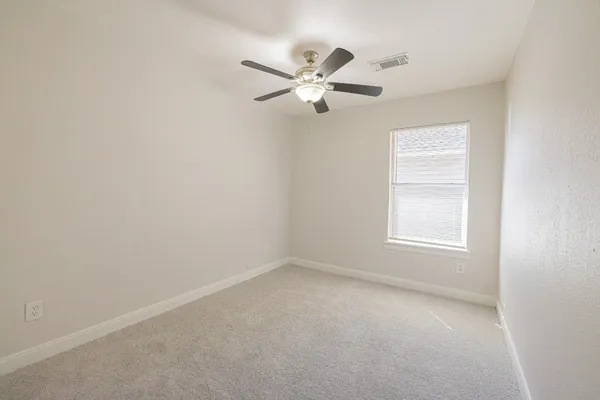 an empty room with windows and fan