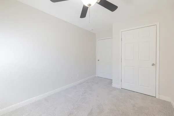 an empty room with a ceiling fan and a window