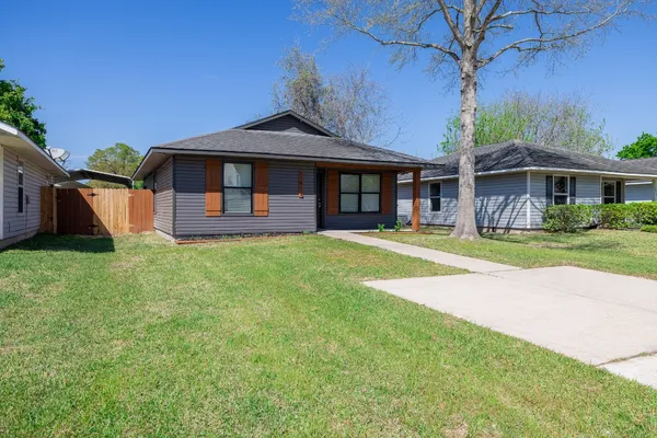 a front view of a house with a garden and trees