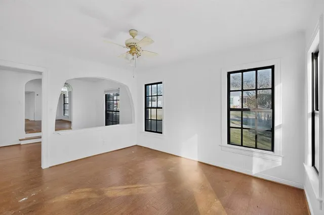 a view of an empty room with window and wooden floor