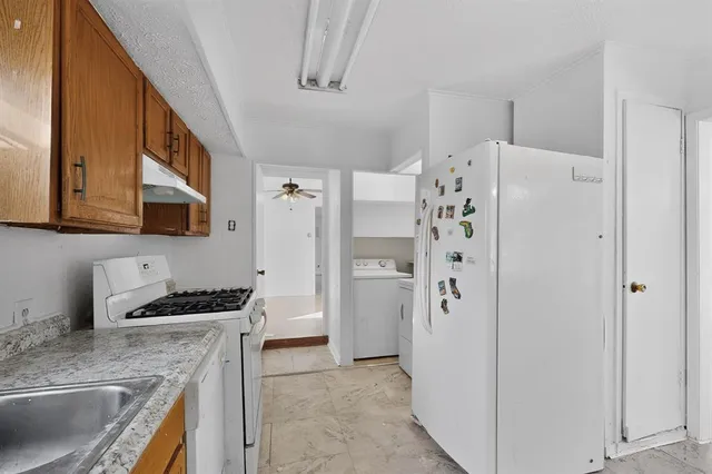 a kitchen with stainless steel appliances granite countertop a refrigerator a stove and a sink