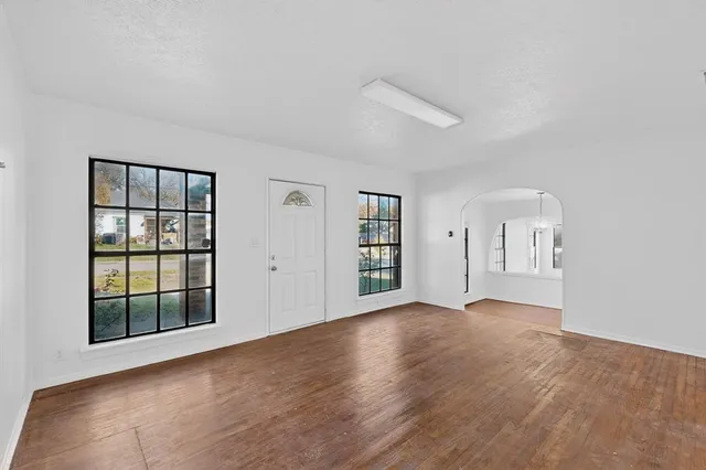 a view of an empty room with a window and wooden floor
