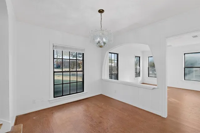 a view of an empty room with chandelier and windows