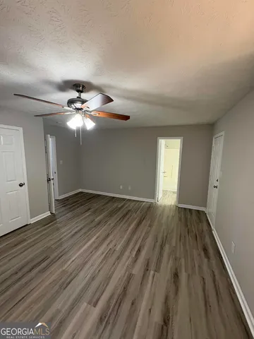 a view of an empty room with wooden floor and window