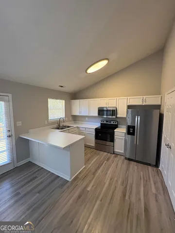 a large white kitchen with a large counter top and stainless steel appliances