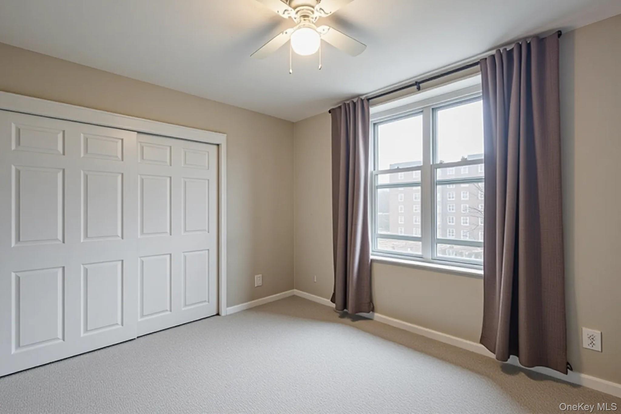 209-25 18th Avenue, Unit 3F Queens, NY 11360 - Photo 16 of 28 an empty room with chandelier fan and windows