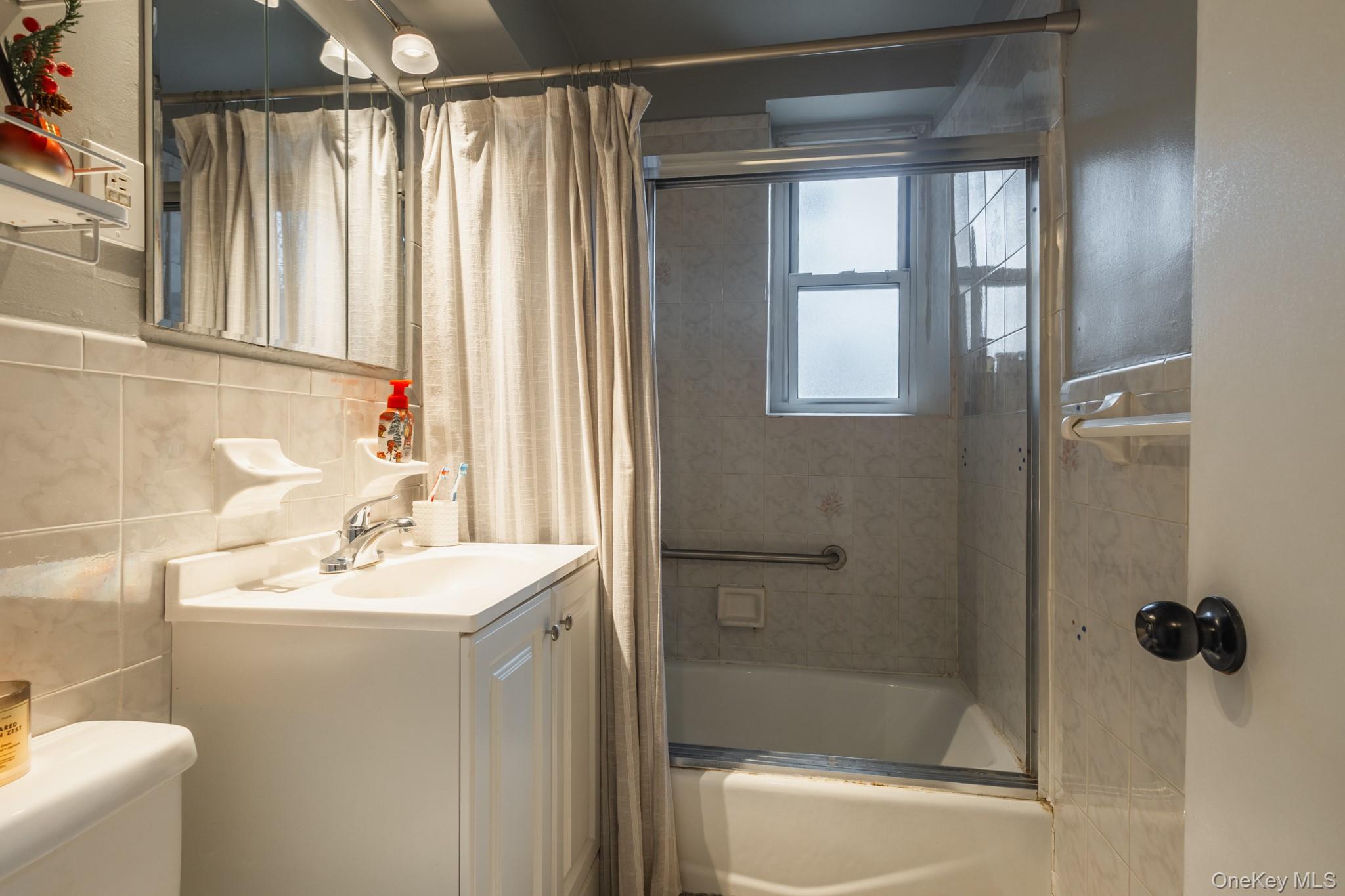 209-25 18th Avenue, Unit 3F Queens, NY 11360 - Photo 21 of 28 a bathroom with a sink mirror and shower