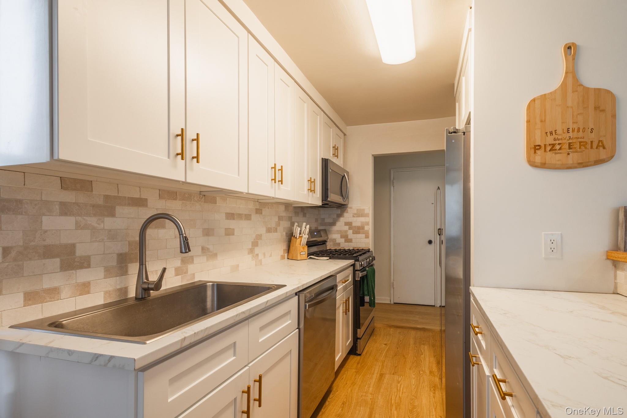209-25 18th Avenue, Unit 3F Queens, NY 11360 - Photo 8 of 28 a kitchen with a sink cabinets and a stove