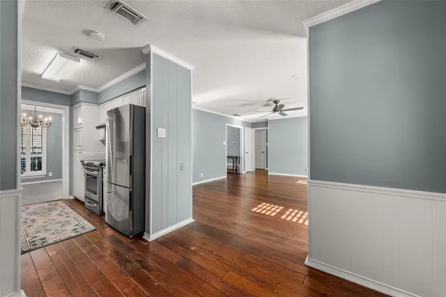 a view of a hallway with wooden floor and a kitchen space