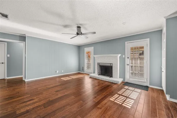 a view of an empty room with wooden floor fireplace and a window