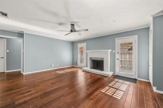 a view of an empty room with wooden floor fireplace and a window