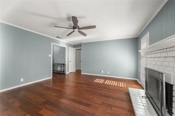 a view of an empty room with wooden floor and a fireplace