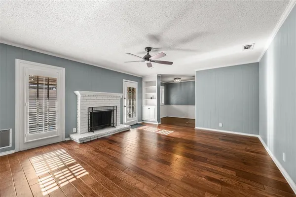 a view of an empty room with wooden floor fireplace and a window