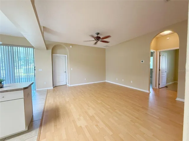 a view of empty room with wooden floor and fan