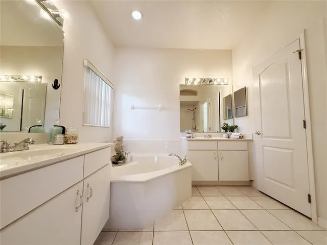 a bathroom with a double vanity sink mirror and bathtub