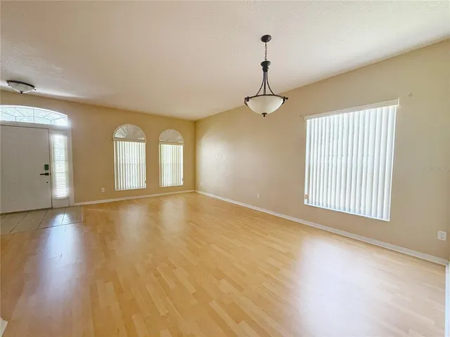 a view of an empty room with chandelier and wooden floor
