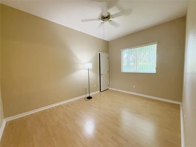 an empty room with a chandelier fan and a window