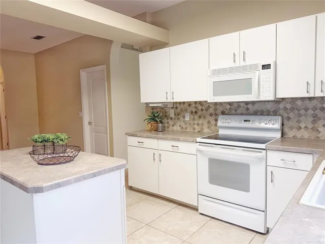 a kitchen with granite countertop white cabinets and white appliances