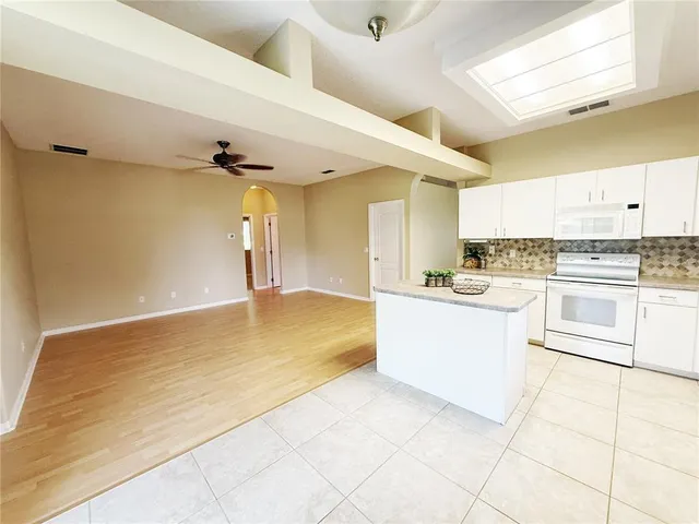 a large white kitchen with a refrigerator a stove top oven and white cabinets