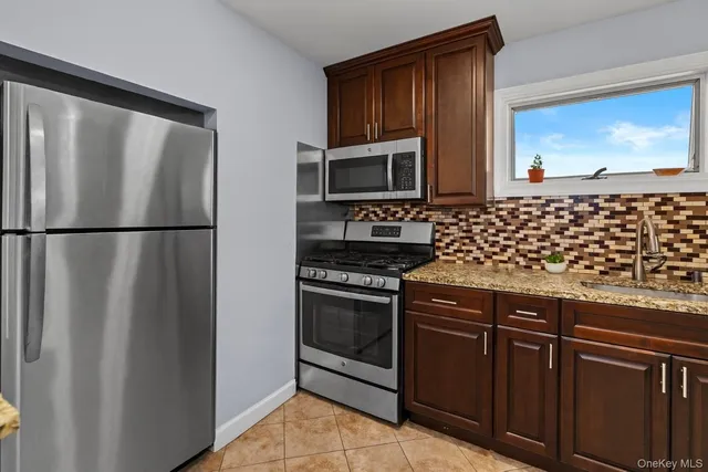 a kitchen with granite countertop a refrigerator stove and microwave