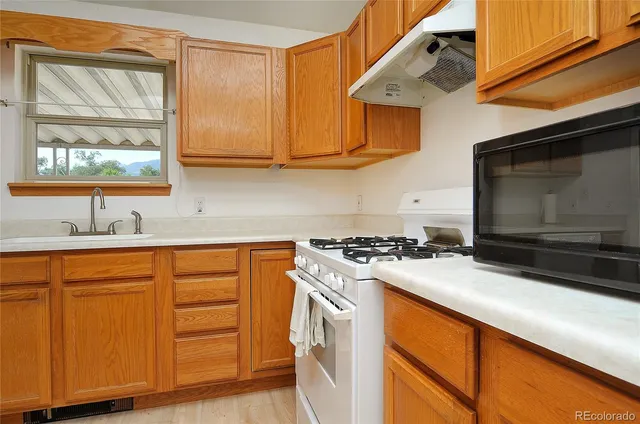 a kitchen with stainless steel appliances granite countertop a stove a sink and a microwave