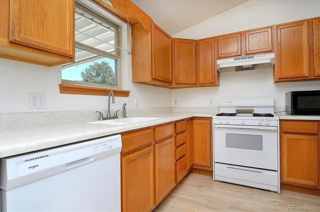 a kitchen with stainless steel appliances granite countertop a sink a stove and a refrigerator