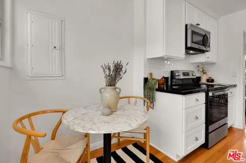 a kitchen with stainless steel appliances granite countertop a stove a microwave a sink and white cabinets