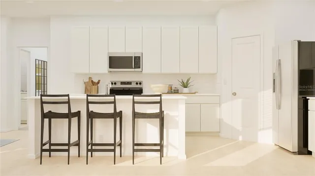 a kitchen with white cabinets and chairs