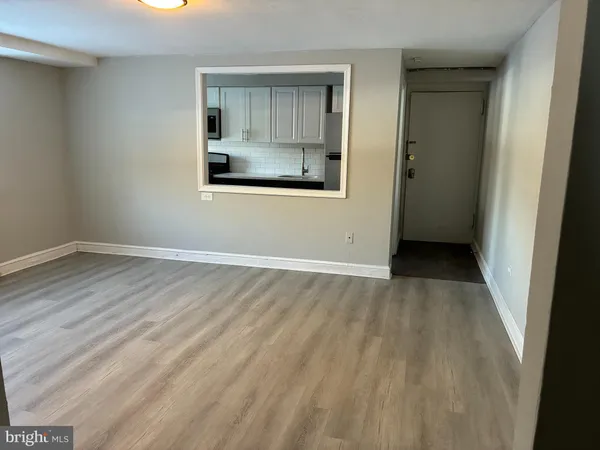 a view of an empty room with wooden floor and a window