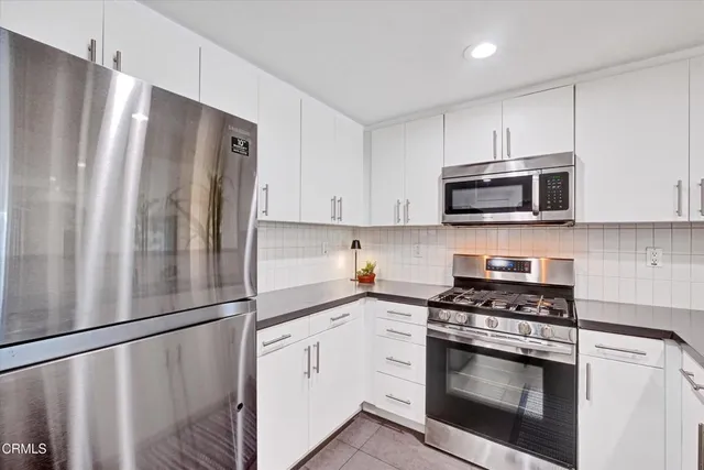 a kitchen with stainless steel appliances white cabinets white stove a refrigerator and a microwave
