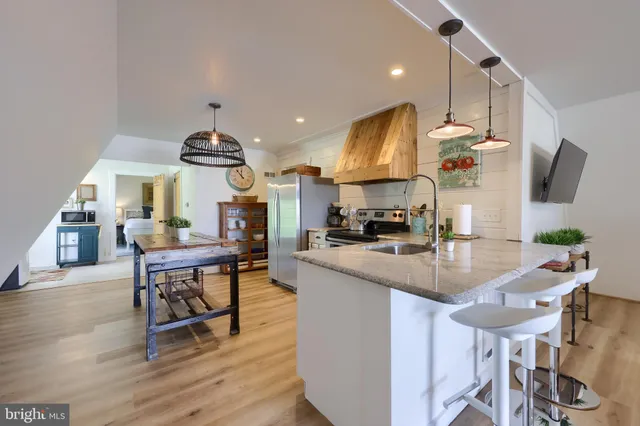 a kitchen with stainless steel appliances kitchen island granite countertop a table chairs and a refrigerator