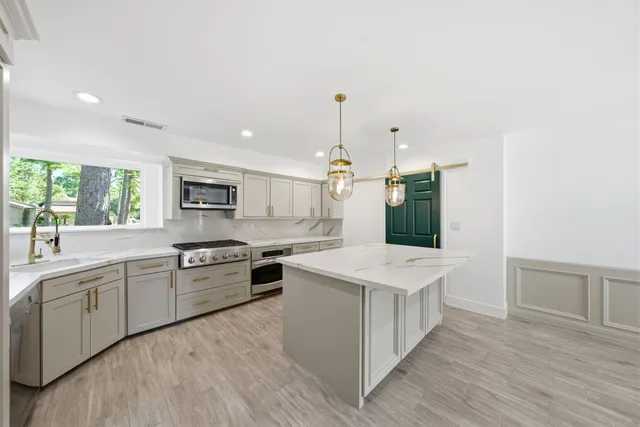 a large kitchen with stainless steel appliances granite countertop a lot of counter space and wooden floors