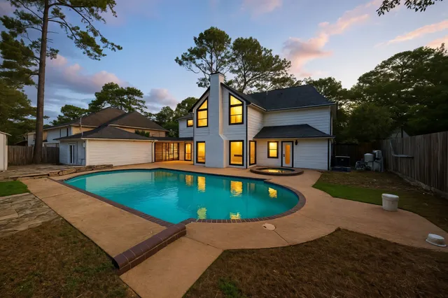 a front view of house and yard with swimming pool and trees in the background