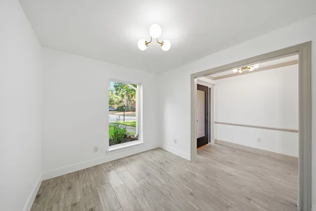 an empty room with wooden floor cabinet and windows