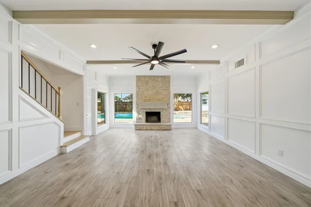 a view of a livingroom with a fireplace a ceiling fan and wooden floor