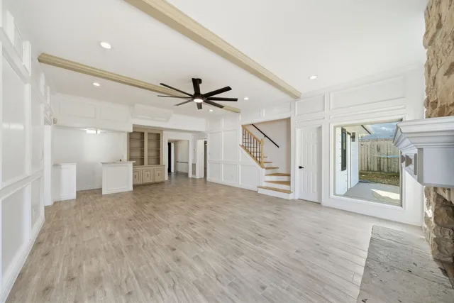 a view of a livingroom with a ceiling fan wooden floor and staircase