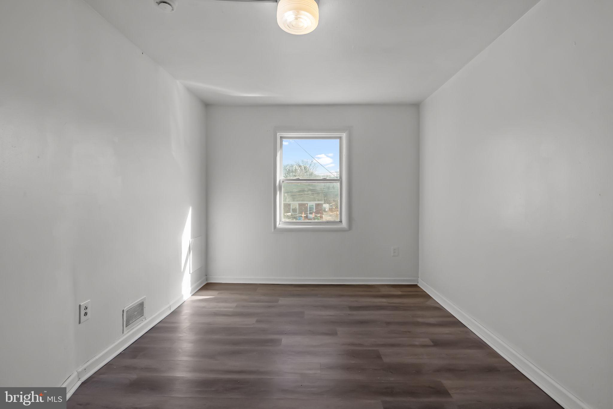 5708 Mitchell Road Levittown, PA 19057 - Photo 21 of 23 a view of an empty room with wooden floor and a window