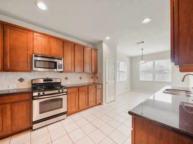 a kitchen with stainless steel appliances granite countertop a stove a sink and a microwave