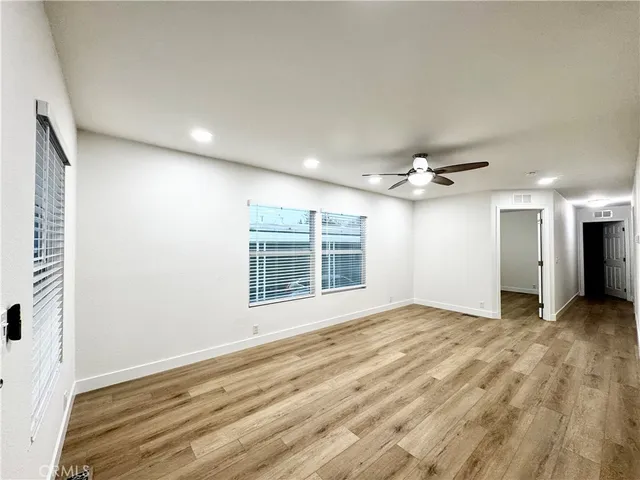 a view of an empty room with a window and wooden floor