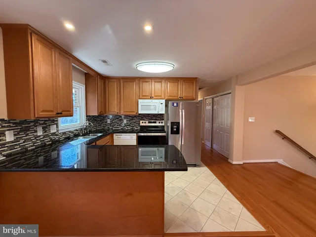 a kitchen with granite countertop a refrigerator and a stove top oven