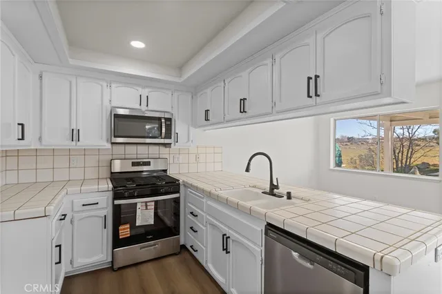 a kitchen with granite countertop white cabinets and appliances