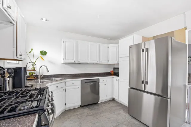 a kitchen with stainless steel appliances granite countertop a refrigerator sink and white cabinets