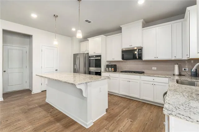 a large kitchen with stainless steel appliances granite countertop a stove a sink and a refrigerator