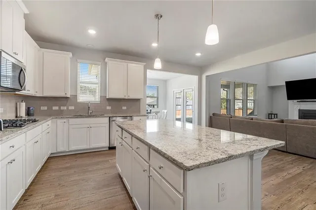 a kitchen with granite countertop cabinets a sink dishwasher a stove and a refrigerator