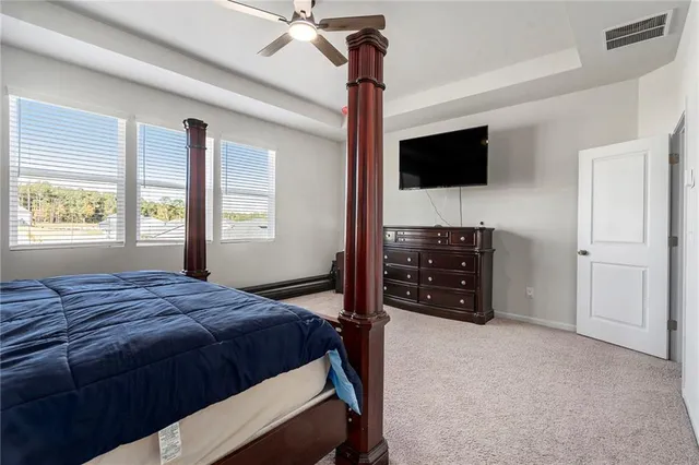 a bedroom with a bed a flat tv screen and a dresser