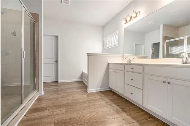 a spacious bathroom with a double vanity sink a mirror and a shower
