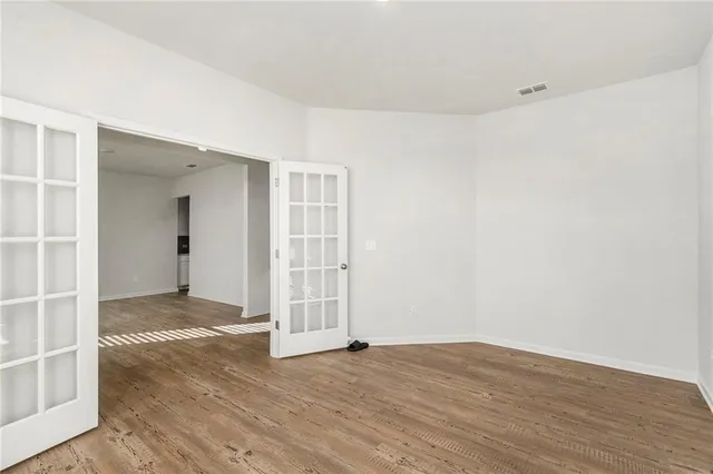 an empty room with wooden floor and windows