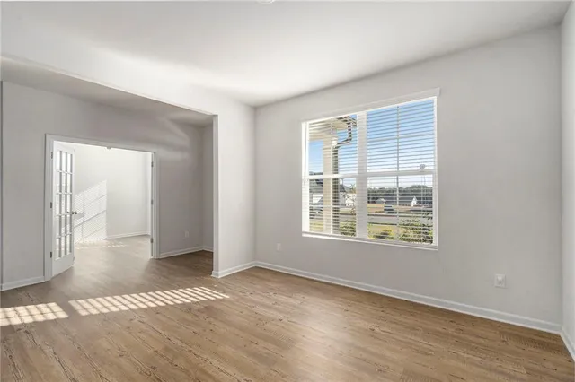 a view of an empty room with wooden floor and a window