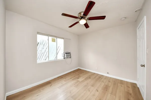 a view of empty room with wooden floor and window