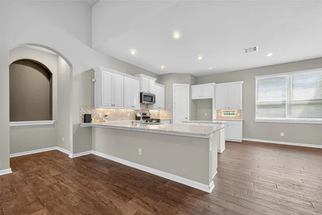 a kitchen with granite countertop white cabinets and stainless steel appliances
